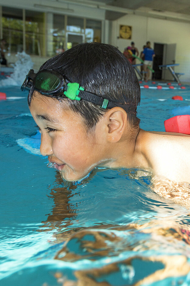 Junge lernt schwimmen im Hallenbad