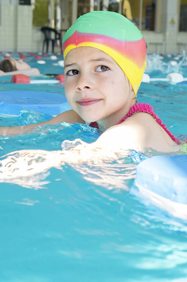 Mädchen lernt schwimmen im Hallenbad