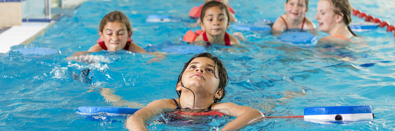 Kinder im Hallenbad lernen schwimmen